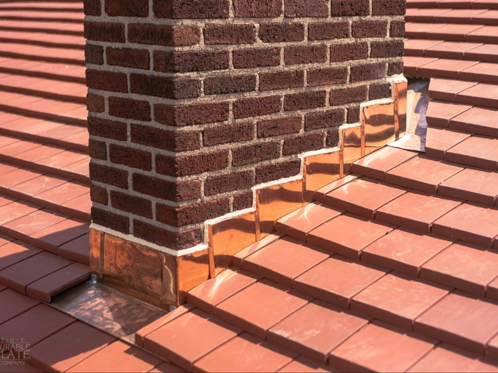 gotowy komin z dachówką kominową zakończony komin w pełni obudowany dachówkami kominowymi harmonijnie z czerwonym dachem