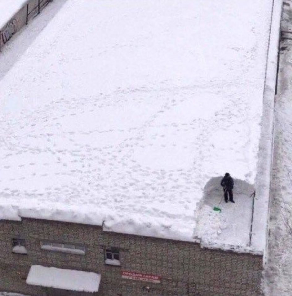 Latarka oświetlająca dach przed pracą ukazując grube warstwy lodu i śniegu