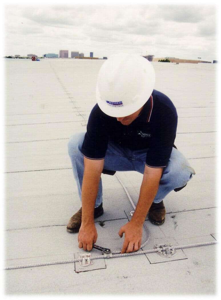 Podłączanie przewodu odgromowego do masztu piorunochronnego na szczycie dachu